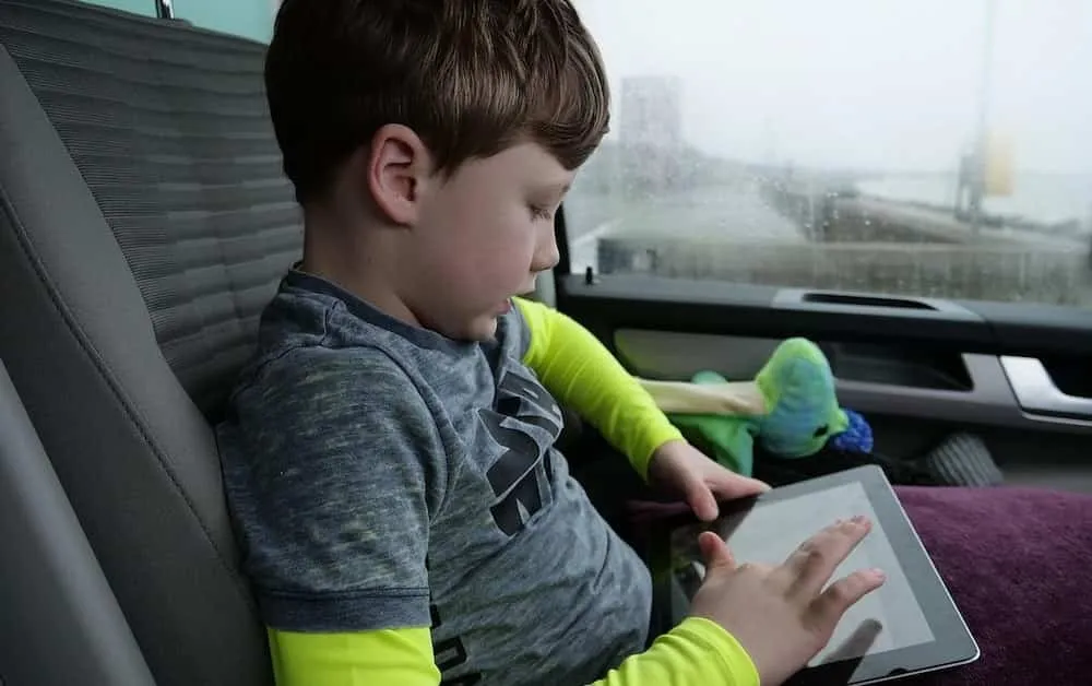 child in back seat with tablet
